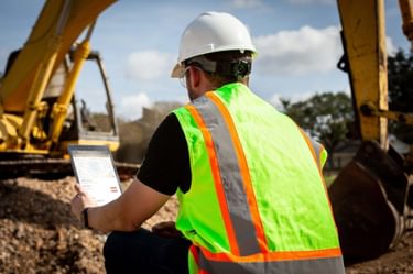 A worker at a construction site looking at a tablet.