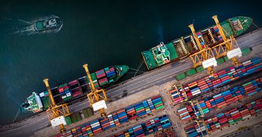 An aerial shot of a port with ships and containers.