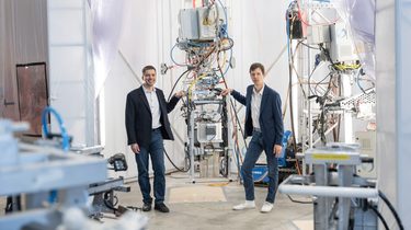 Two men standing by a robot